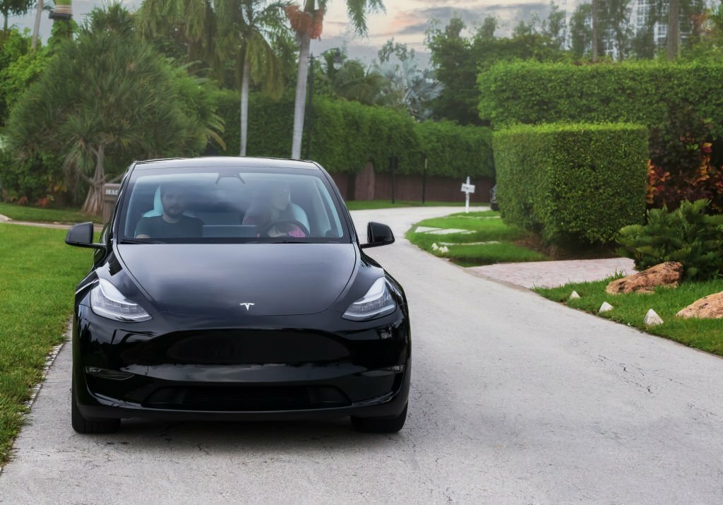 Miami, FL, United States - September 13, 2021: Tesla Model Y parked on the street with two people. This model is the first SUV from Tesla brand. The electric Model Y has all-wheel drive and seating for seven adults.
